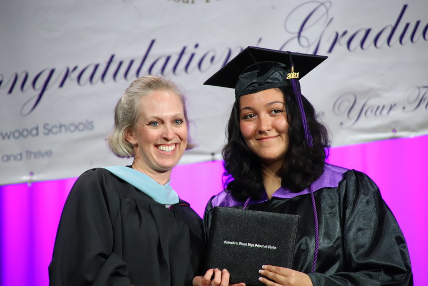 A student poses with a staff member May 21 on stage at the Colorado's Finest High School of Choice graduation ceremony in the school's auditorium in Englewood.
